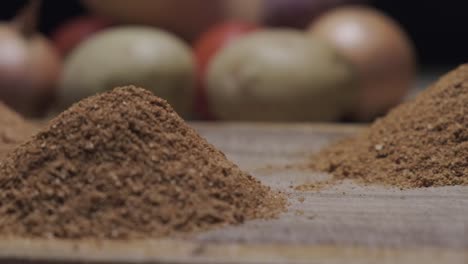 Close-up-left-pan-of-spice-heaps-with-vegetable-in-the-background