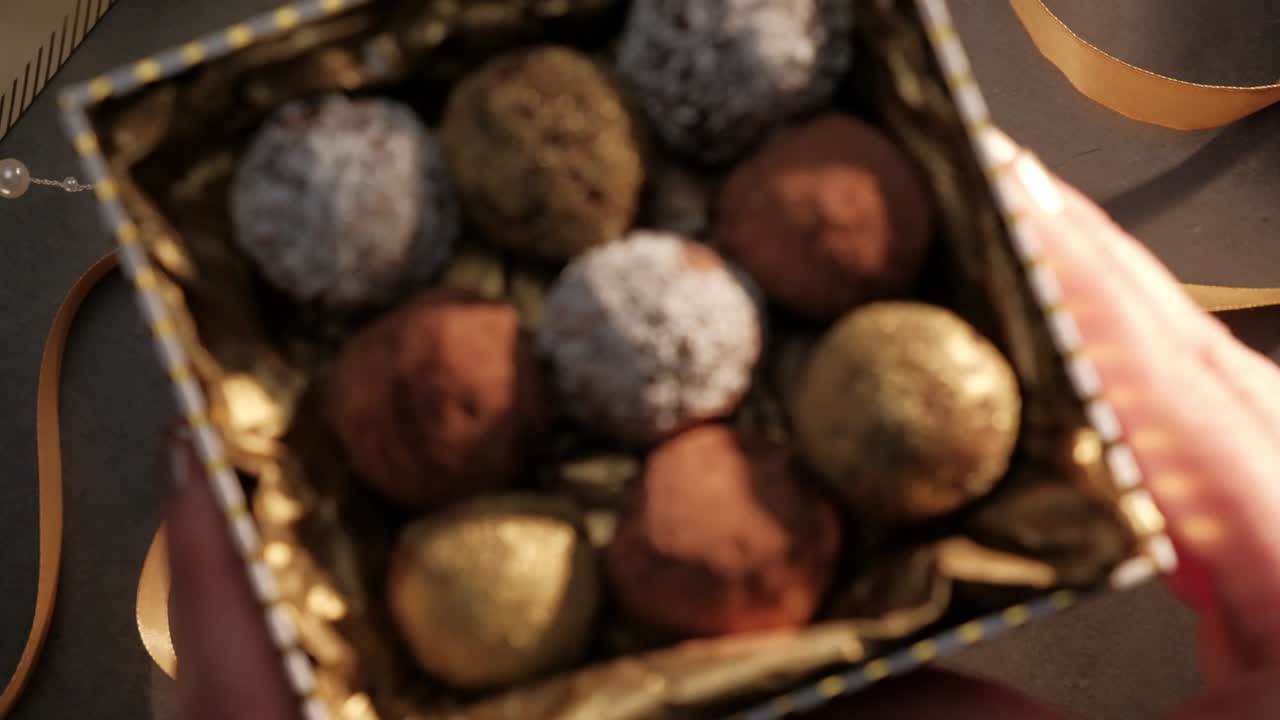 manos sosteniendo un regalo, variedad de trufas de chocolate, entrando y saliendo de foco