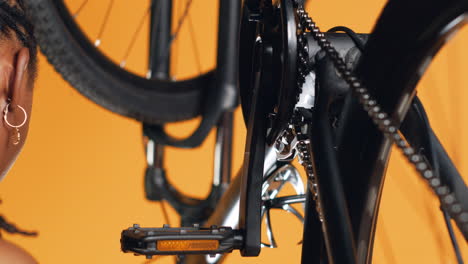 woman dismantling bicycle parts to patch them up, studio background