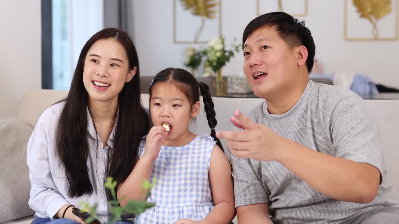 Happy family enjoys movie night, sharing popcorn in a bright, cozy living room together
