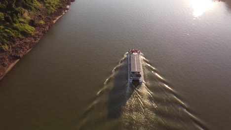 a tracking aerial view of a tourist boat on the iguazu river at sunset