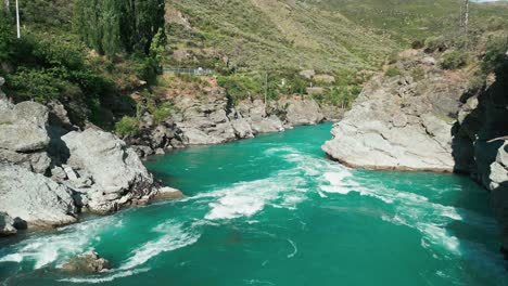 dron entre dos montañas paso bajo sobre río furioso