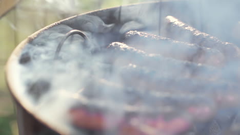 slow motion of charred gristly sausage grilling on smokey bbq grill