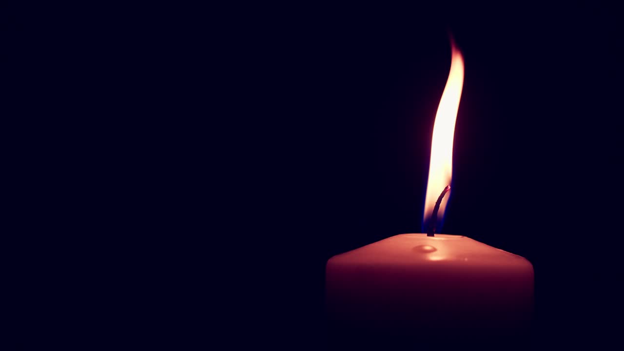 одиночная большая желтая свеча горит и гаснет, изолированная на черном фоне