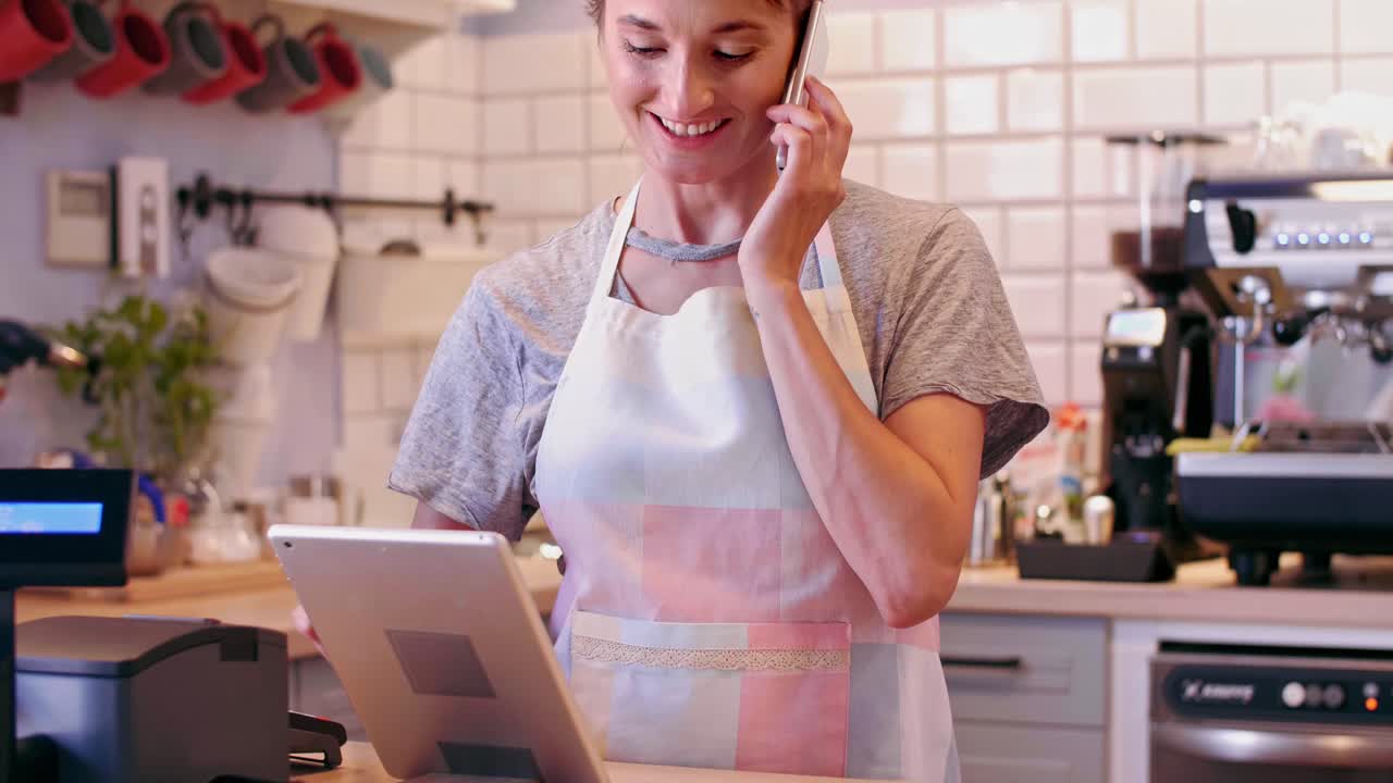 barista multitarea hablando por teléfono móvil y usando tableta digital