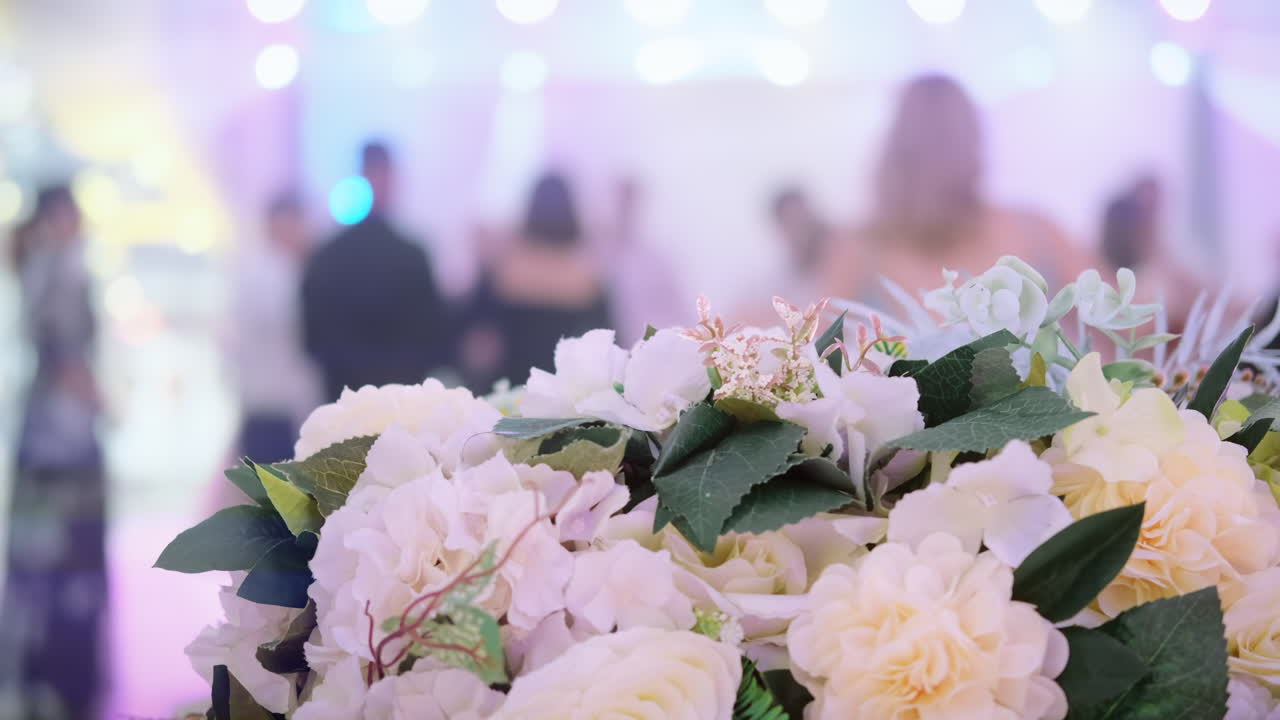 Ospiti che ballano la Hora, una danza nazionale moldava, a un matrimonio. Bouquet in primo piano. Luci del palco