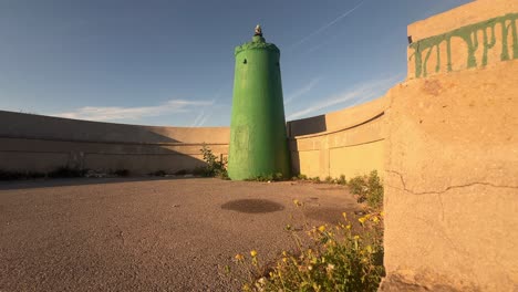 a concrete facility with green-tinted water silos, observed along the shores of spain, showcasing the integration of human-made structures with coastal environments