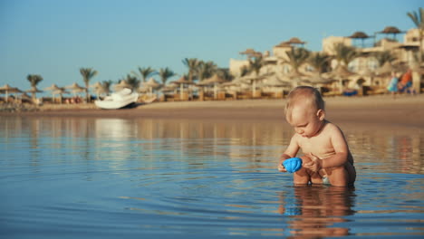 Molliges-Baby,-Das-Mit-Spielzeug-Im-Meerwasser-Spielt.-Kind-Spritzt-Wasser-Am-Meer
