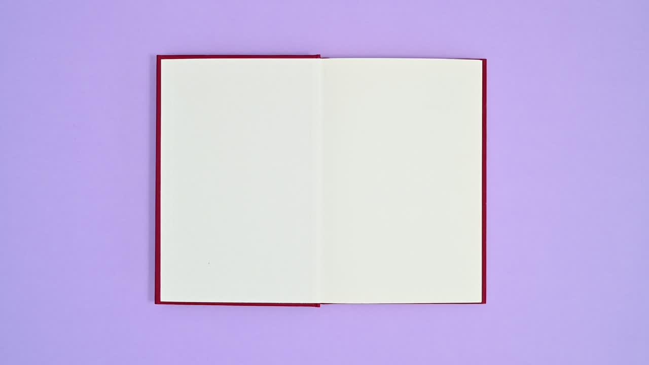 Deep red hardcover book appear on purple theme and opens. Stop motion flat lay