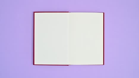 deep red hardcover book appear on purple theme and opens. stop motion flat lay