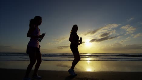 chicas chinas asiáticas rehidratándose en la playa al amanecer