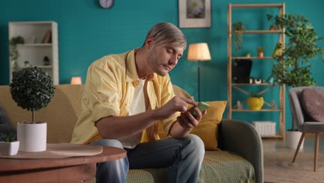 man using smartphone on couch in living room