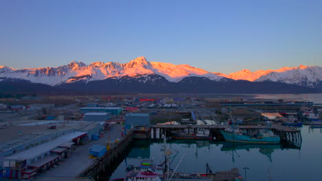 Drone-flying-up-over-Seward-Boat-Harbor-towards-the-mountains-at-sunset-in-Seward-Alaska