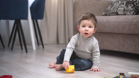 baby playing on the floor with building blocks, then gets up and takes his first steps to the camera