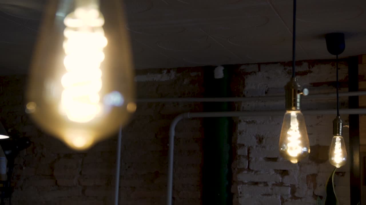 Illuminated Pendant Lights Hanged On Ceiling Inside Rustic Cafe Restaurant. - close up