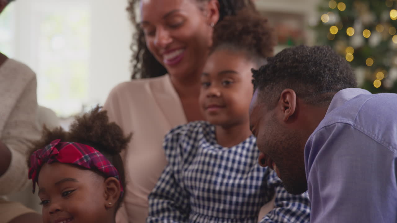 Famiglia multigenerazionale che celebra il Natale a casa e apre i regali insieme