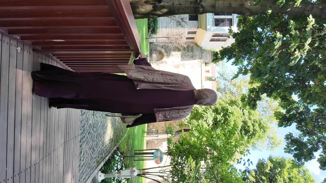 Woman in purple abaya looking at a lush garden