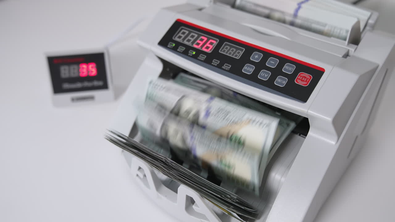 Counting American one hundred dollar bills in the bank equipment. White cash counting machine working. High angle view.