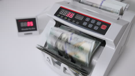 counting american one hundred dollar bills in the bank equipment. white cash counting machine working. high angle view.