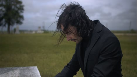 young, religious man in black suit worshipping and praying in front of christian cross