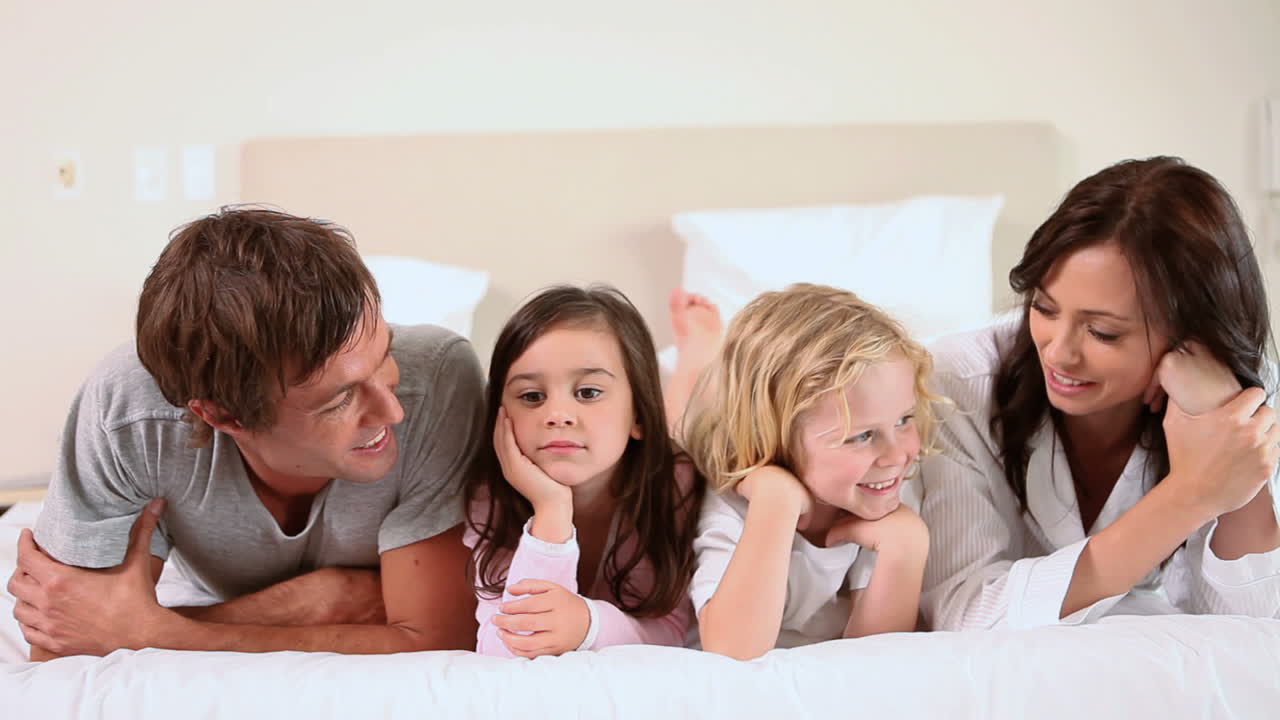 침대 에 함께 누워 있는 가족