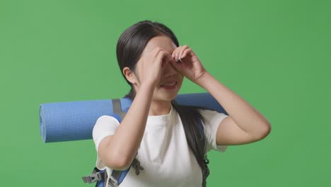 young woman with backpack looking through fingers