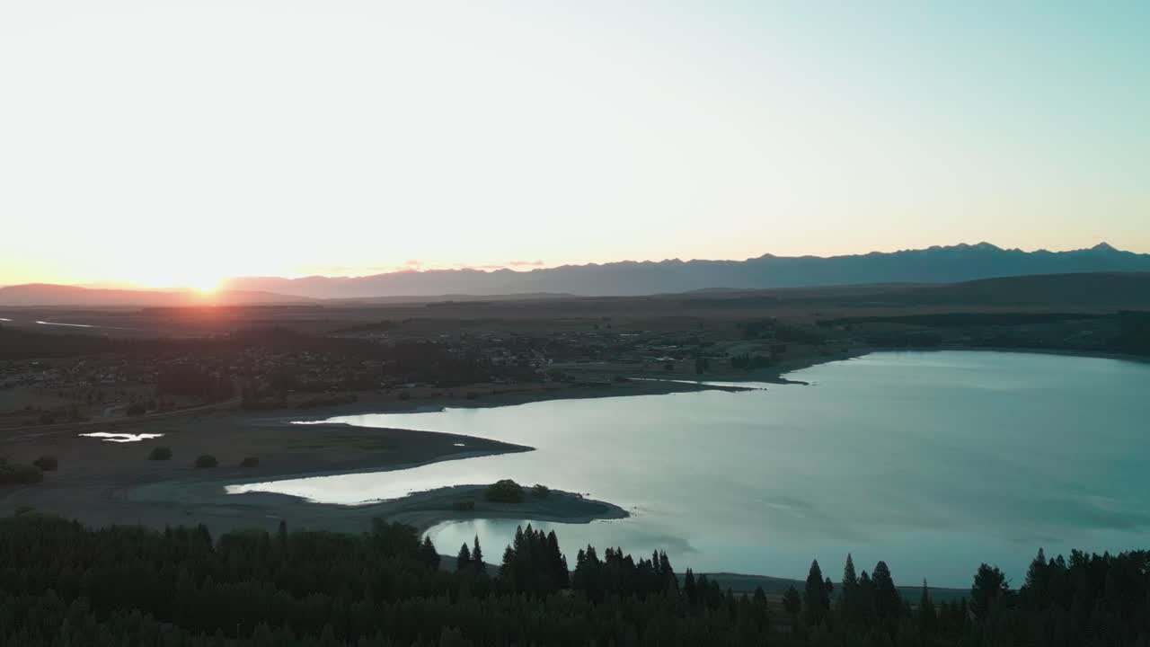 drone puesta de sol sobre el lago tekapo con cielo despejado y agua azul