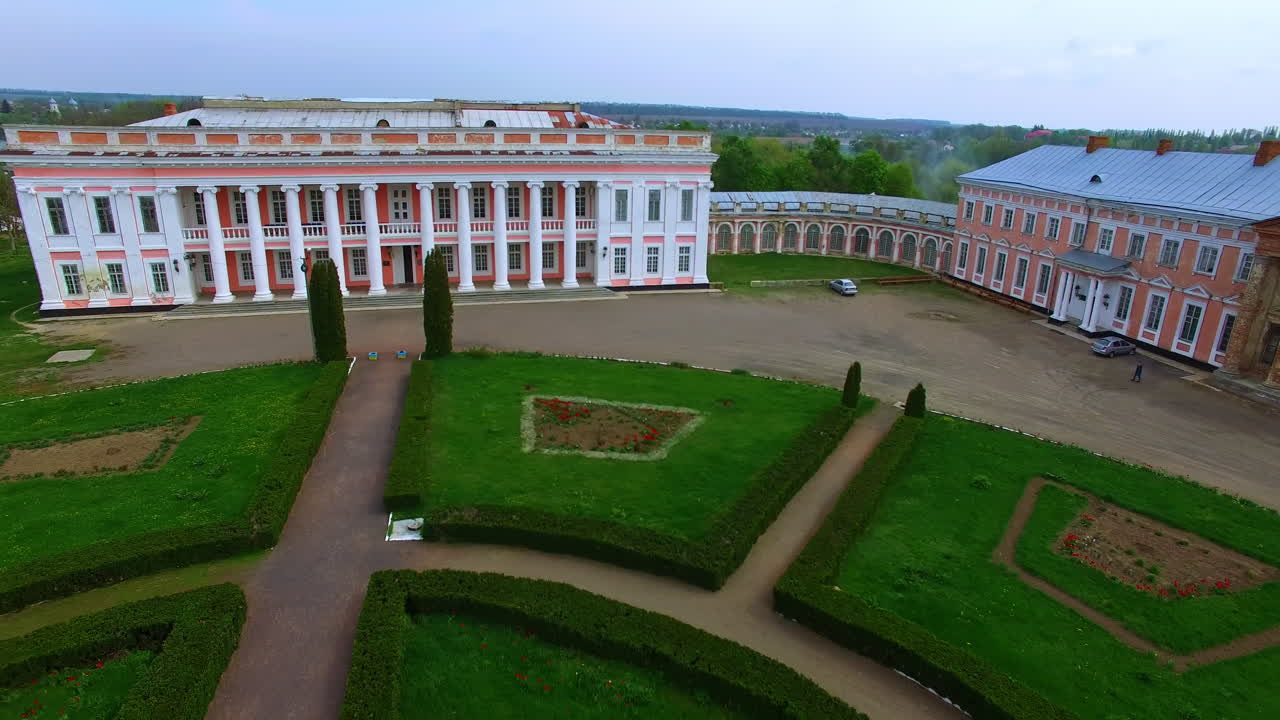 Going up and distancing from the historic palace. Green flower beds and trees at backdrop are opening to the view.
