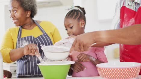 Abuelos-Afroamericanos-Sonrientes-Horneando-Con-Su-Nieta-Feliz-En-La-Cocina,-En-Cámara-Lenta