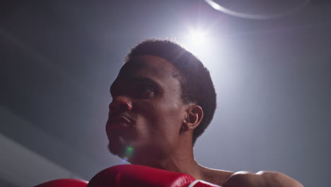 close up of boxer wearing gloves in ring making aggressive gesture before start of boxing match warming up