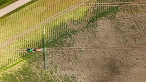 dry brown farmland with visible tractor tire lines and spray trails in sunny summer weather