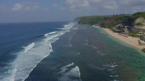 melasti bali beach aerial drone view drone is moving forward, and waves are coming in the water
