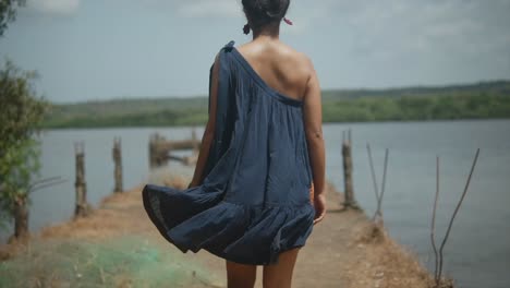 A-woman-walking-away-form-the-camera-on-a-pier-in-a-rural-area