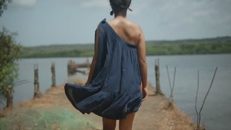 a woman walking away form the camera on a pier in a rural area