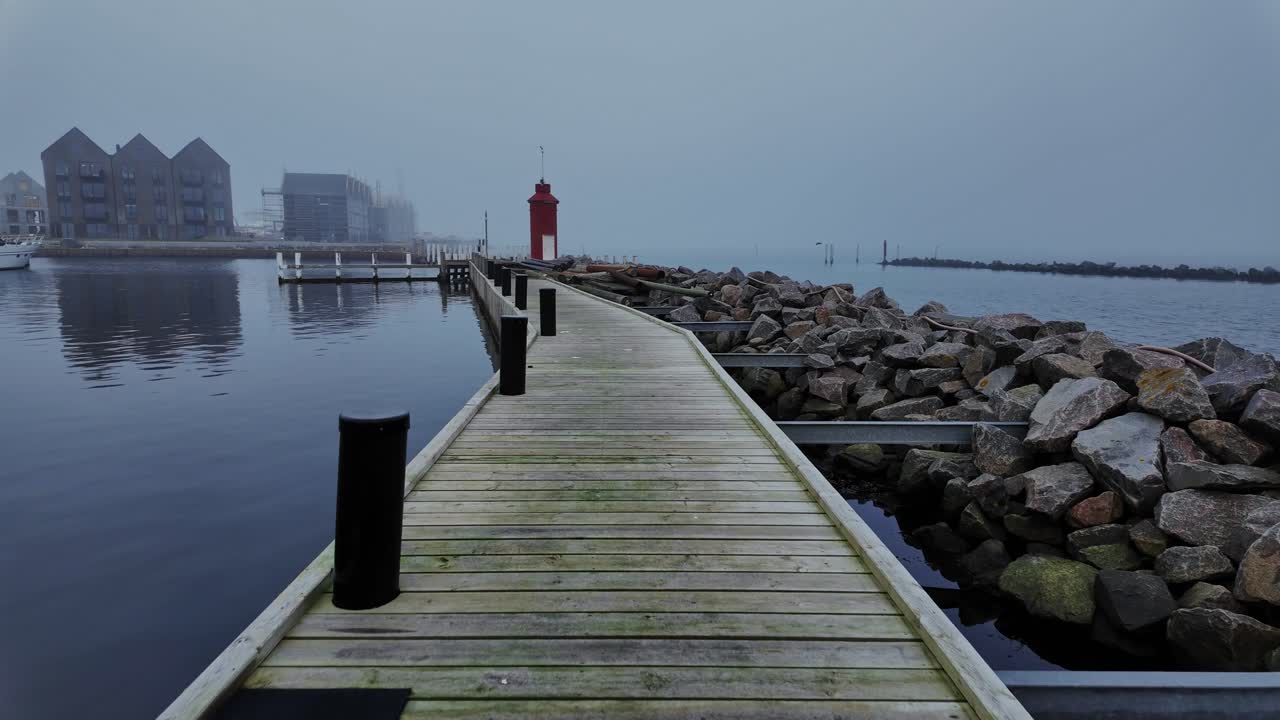 On a foggy day, the wooden footbridge stood silently, with ship ballast poles lined up along the shore, barely visible through the mist.