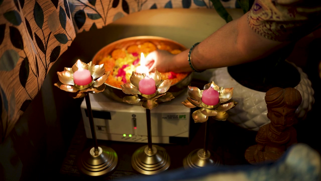 Hand Placing Decorative Candle Among Marigold Flowers for Diwali Celebration