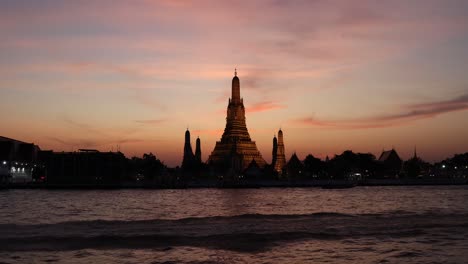 boat passing by a temple at sunset