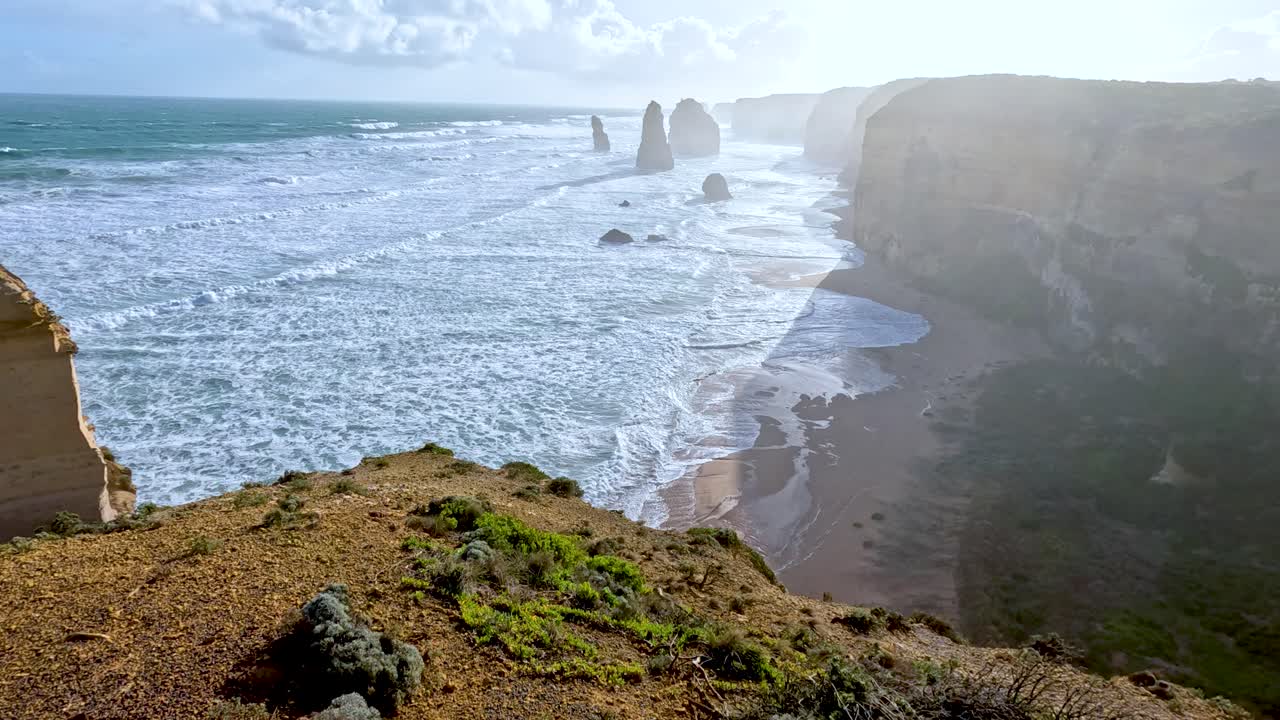 A sweeping view of the Twelve Apostles along the Great Ocean Road, showcasing rugged cliffs and ocean waves under bright sunlight