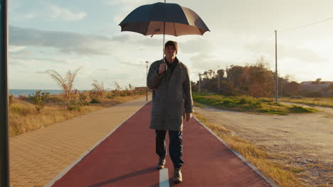 man walking slowly on the bike lane with an umbrella under the sun