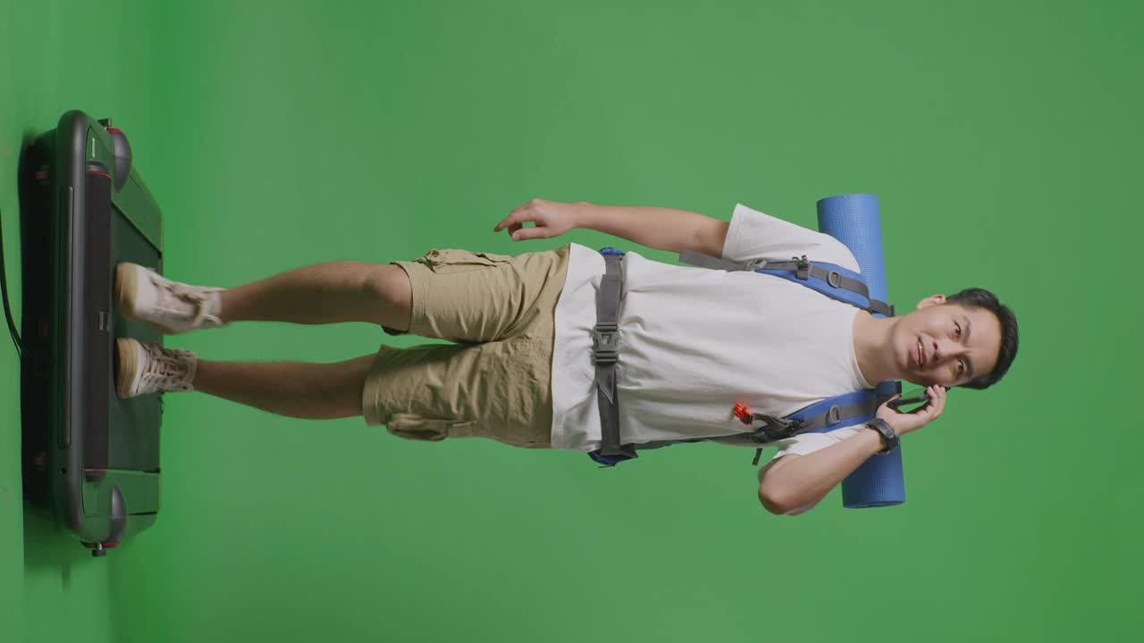 hombre caminando en una cinta de correr mientras habla por teléfono y lleva una mochila