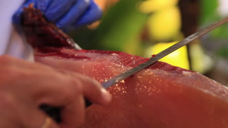 close up shot of an expert finely slicing some spanish serrano iberico jamon ham