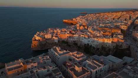 golden evening light in polignano a mare. old town rooftops, white historic houses on cliffs. italy