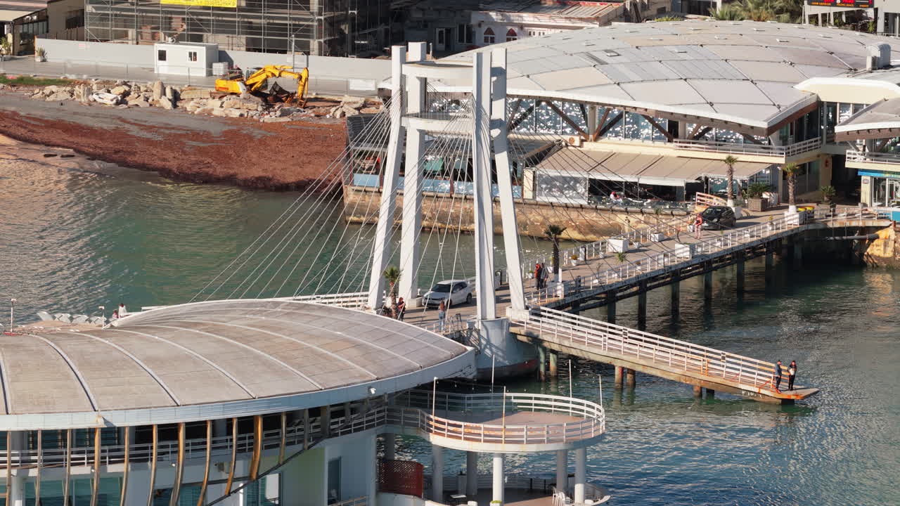 Aerial drone view of the iconic bridge building extending over the turquoise waters of the Adriatic Sea in Durres, Albania