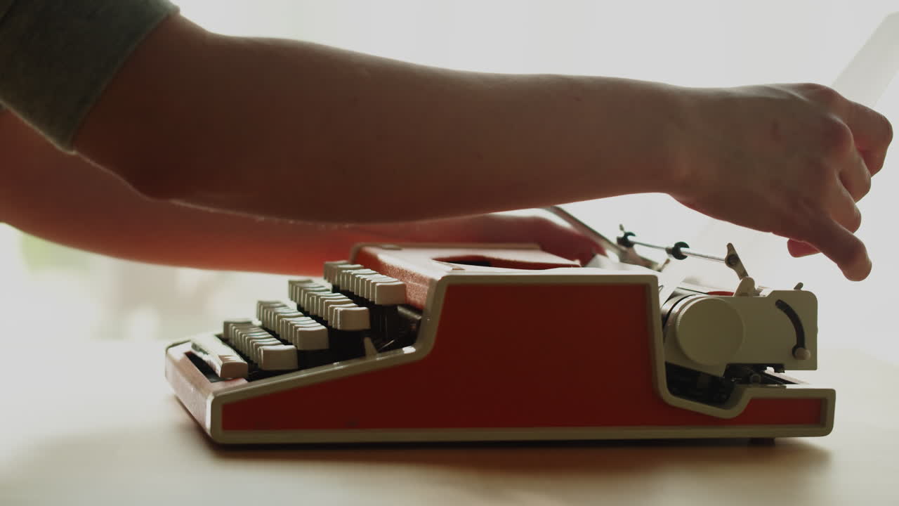 Hands Inserting Paper and Typing on a Vintage Typewriter