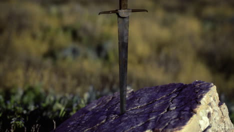 sword embedded in rock at sunset amidst natural landscape