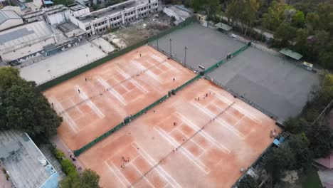 在印度新德里的一座城市日落时,在树木和房子上方拍摄了4k无人机拍摄的草<unk>网球场.