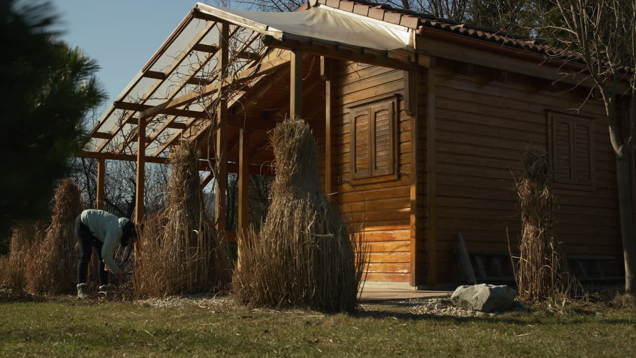 woman working in front of a garden cottage on a sunny spring day