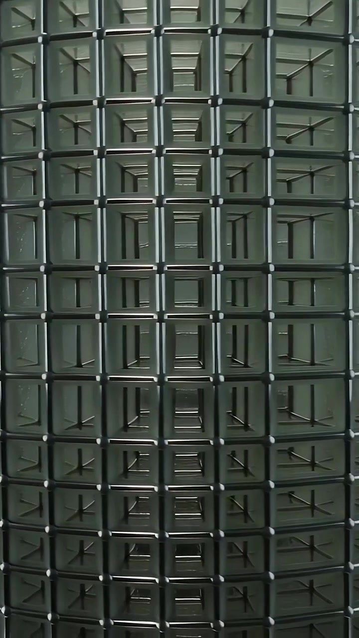 Vertical video: Panning shot tilting and pulling, showing drum embossed grid and rods in workshop