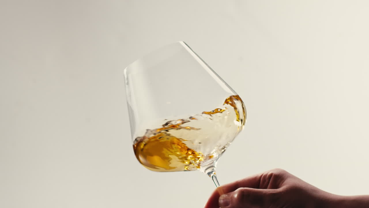 Orange or white wine bottle and glass against a sunset in a peaceful vineyard, pouring of ecological natural wine.