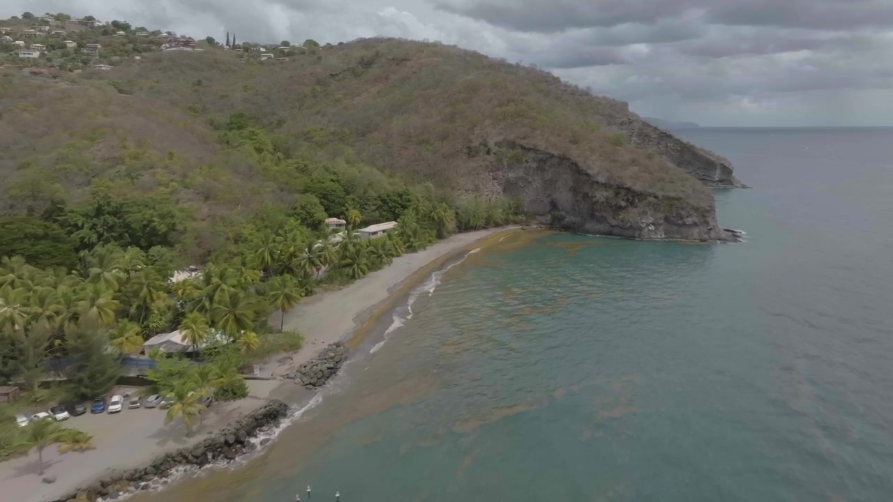 Drone in volo sul bordo dell'oceano, plage du coin in Martinica, Francia, nella regione di Le Carbet, con vista sulla marina, alcune barche e fino al bordo della spiaggia e dei ristoranti